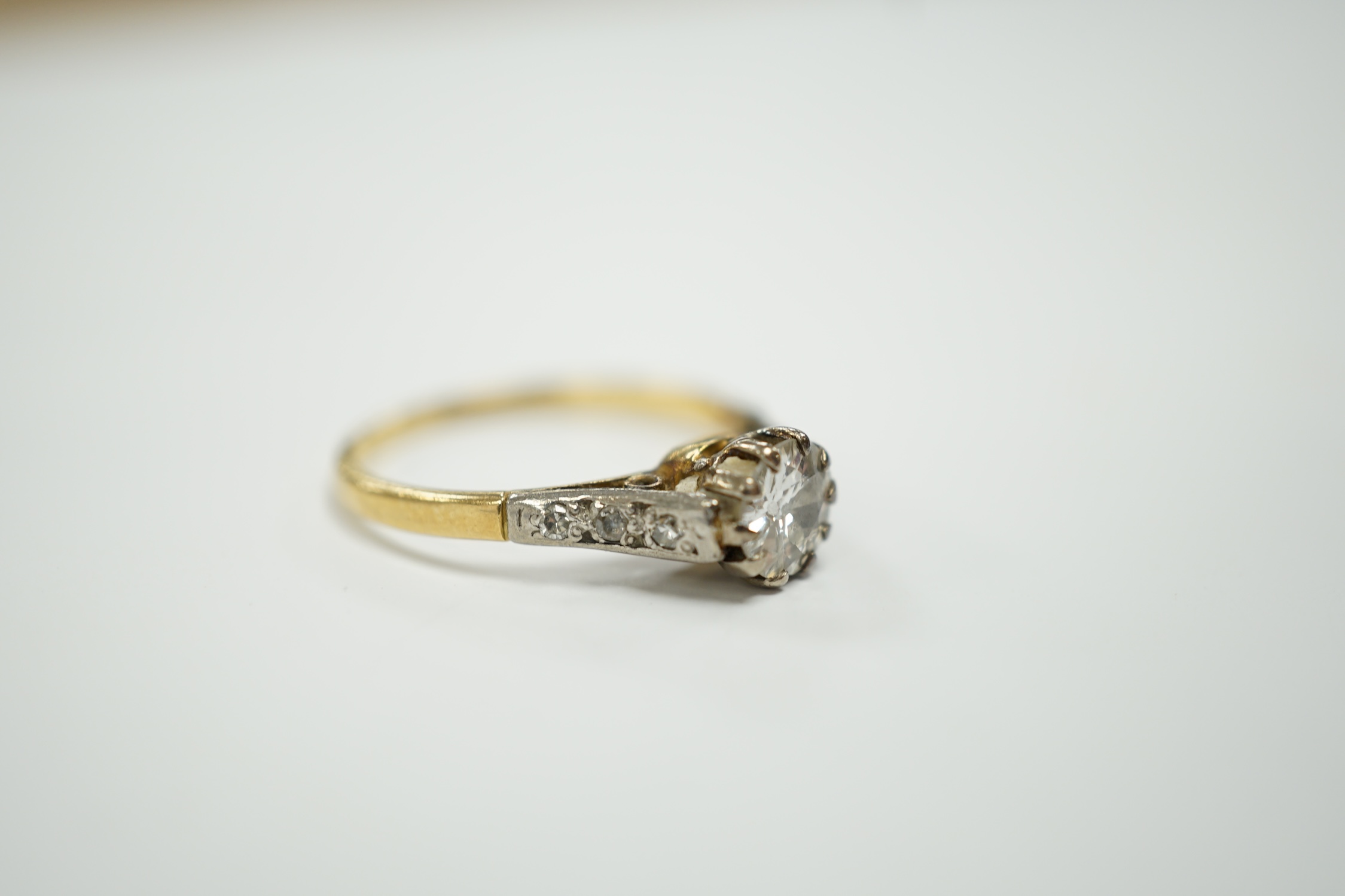 An 18ct, plat and single stone diamond set ring, with diamond chip set shoulders